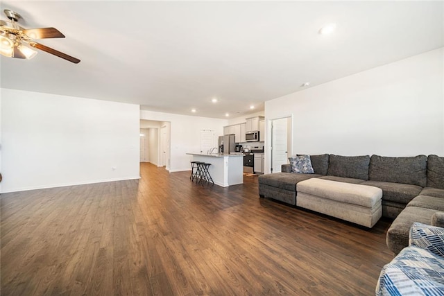 unfurnished living room featuring dark wood-style floors, recessed lighting, a ceiling fan, and baseboards