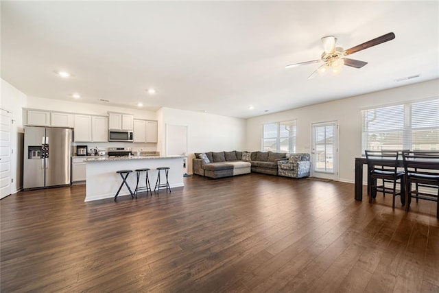 living area with dark wood-style flooring, recessed lighting, visible vents, a ceiling fan, and baseboards