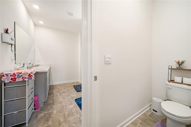 bathroom with toilet, recessed lighting, vanity, and baseboards