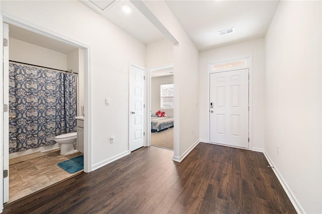 entrance foyer featuring baseboards, visible vents, and dark wood-style flooring