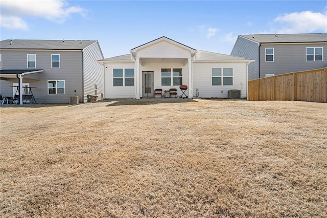 back of property featuring a lawn, fence, and central air condition unit