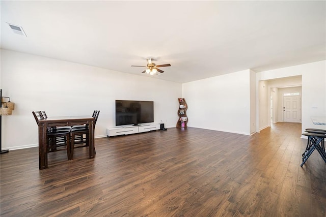 living room featuring ceiling fan, visible vents, baseboards, and dark wood-style flooring