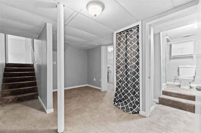 basement featuring a drop ceiling and light colored carpet