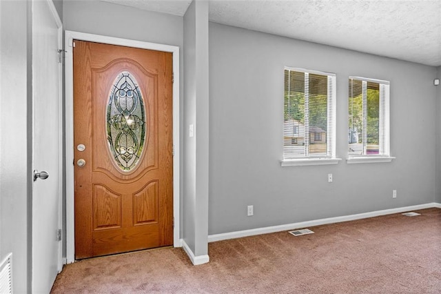 foyer entrance featuring light carpet and a textured ceiling