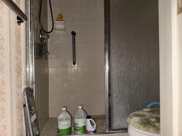 bathroom featuring toilet and a shower with door