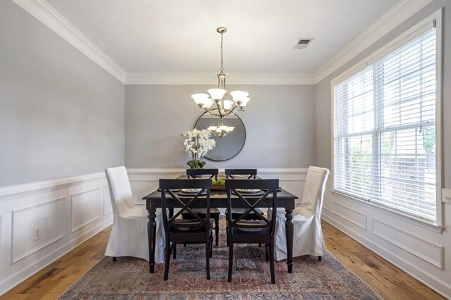 4765 Silver Leaf Dr, Cumming, GA 30040 - dining room featuring a chandelier, wood finished floors, crown molding, wainscoting, and a decorative wall