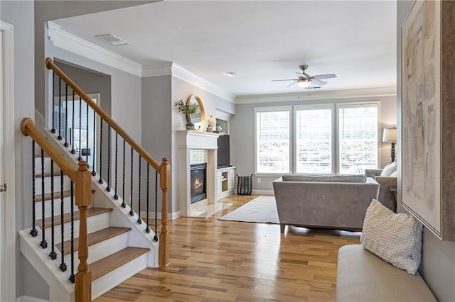 4765 Silver Leaf Dr, Cumming, GA 30040 - living area featuring ceiling fan, a fireplace with flush hearth, light wood finished floors, ornamental molding, and stairway