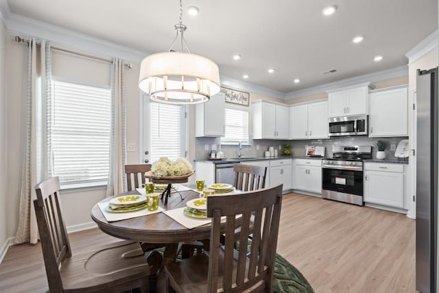 dining space featuring crown molding, sink, and light hardwood / wood-style floors