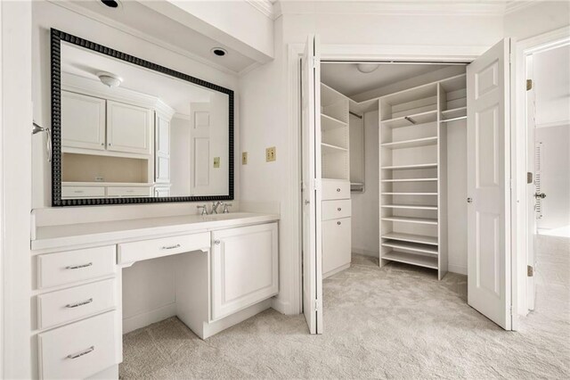 bathroom with a walk in closet, crown molding, and vanity