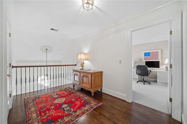 corridor with baseboards, ornamental molding, wood finished floors, and visible vents