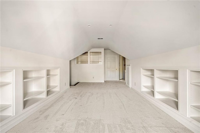 additional living space with built in shelves, vaulted ceiling, carpet flooring, and baseboards