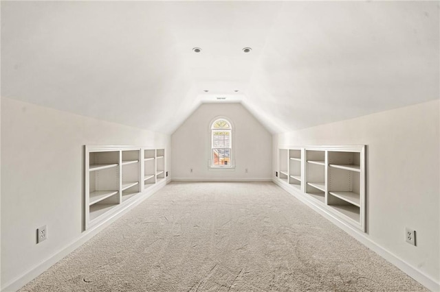 additional living space featuring lofted ceiling, baseboards, carpet flooring, and built in shelves