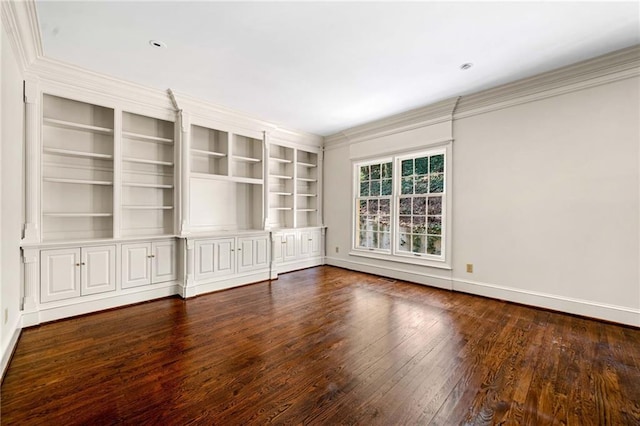 empty room featuring built in shelves, baseboards, crown molding, and wood finished floors