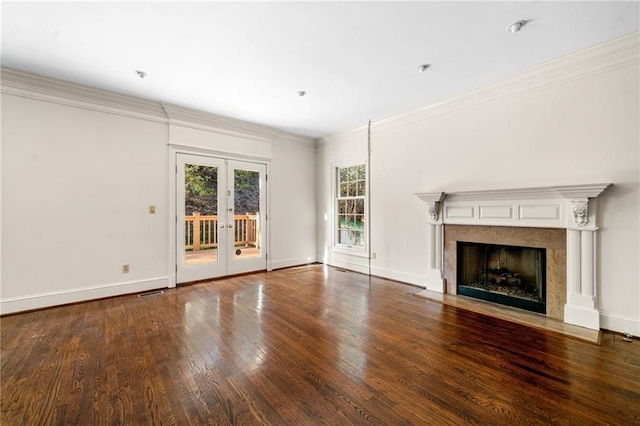 unfurnished living room with a fireplace with flush hearth, wood finished floors, french doors, crown molding, and baseboards