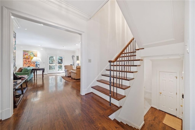 staircase with wood finished floors, baseboards, and ornamental molding