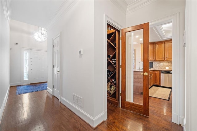 entrance foyer featuring a notable chandelier, crown molding, wood finished floors, and visible vents