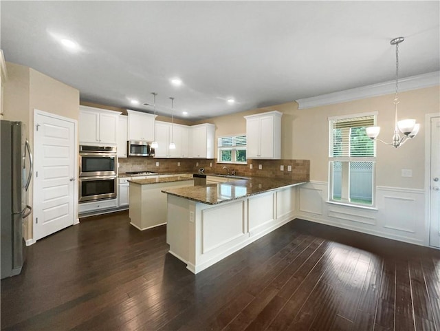 kitchen featuring pendant lighting, stainless steel appliances, white cabinets, and dark hardwood / wood-style flooring