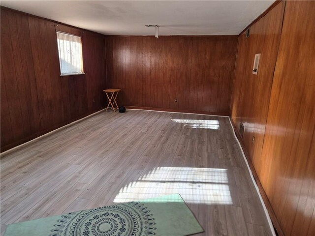 unfurnished room with light hardwood / wood-style floors and wooden walls