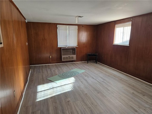 spare room with heating unit, wooden walls, and light wood-type flooring