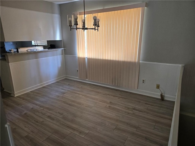 unfurnished dining area with a chandelier and hardwood / wood-style floors