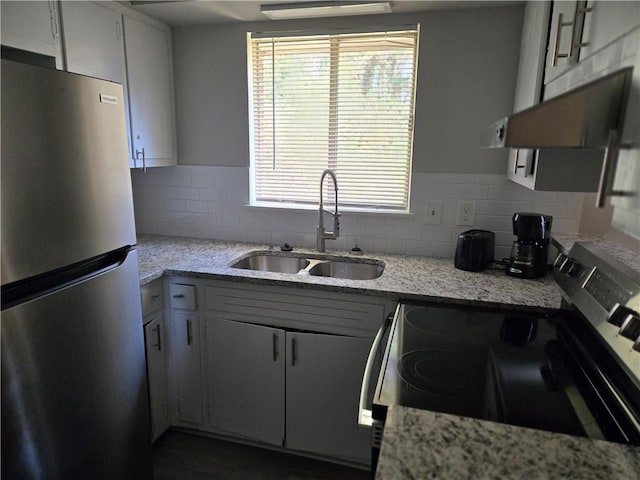 kitchen featuring decorative backsplash, range, sink, and stainless steel refrigerator