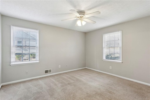 spare room with light colored carpet, a textured ceiling, and ceiling fan