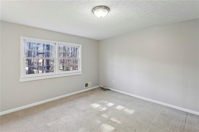 empty room with light carpet and a textured ceiling