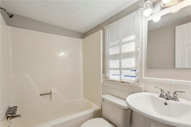 full bathroom featuring sink, shower / bathing tub combination, a textured ceiling, and toilet