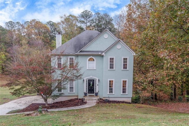 colonial inspired home featuring a front lawn