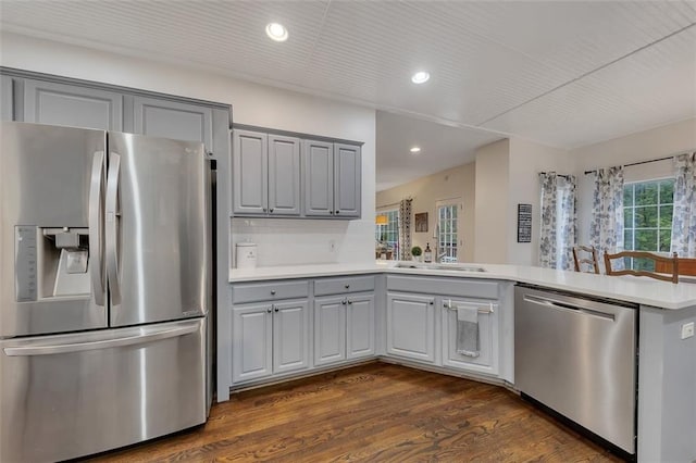 kitchen featuring kitchen peninsula, appliances with stainless steel finishes, gray cabinets, and dark wood-type flooring