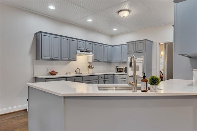 kitchen featuring kitchen peninsula, backsplash, dark hardwood / wood-style floors, and gray cabinetry