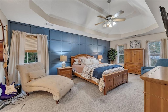 carpeted bedroom with ceiling fan and a tray ceiling