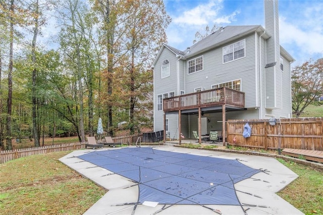 rear view of property featuring a lawn, a patio, and a covered pool