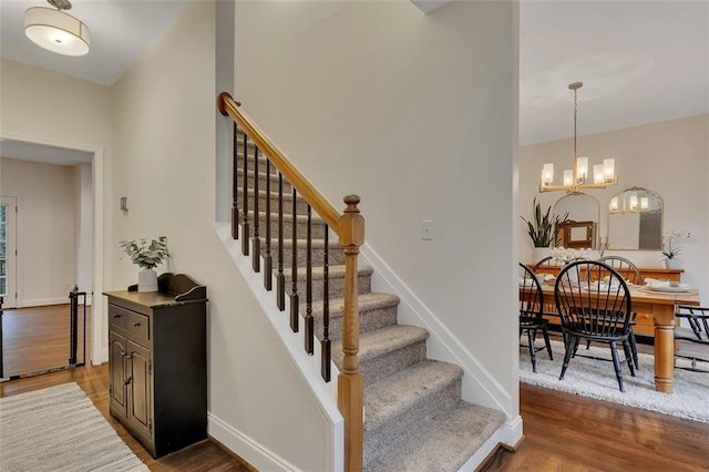 staircase featuring wood-type flooring and an inviting chandelier