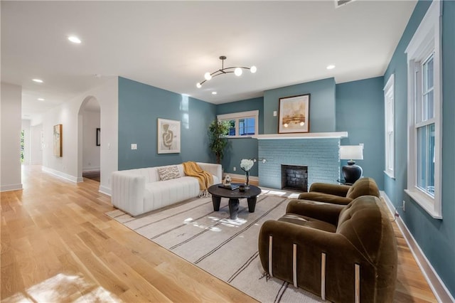 living room with light hardwood / wood-style floors, a chandelier, and a fireplace