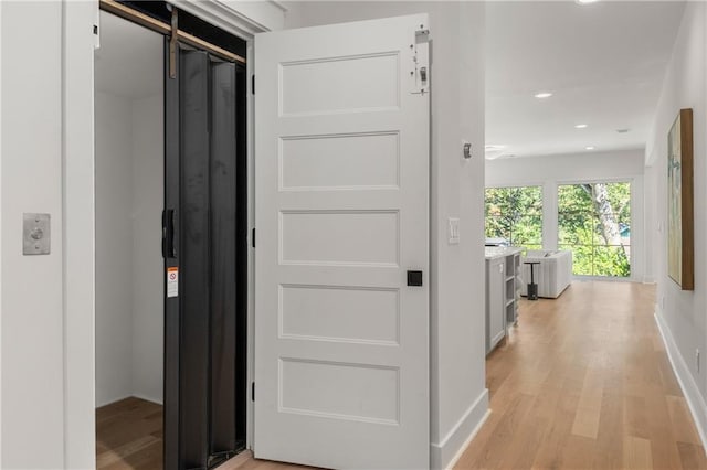 corridor featuring elevator and light hardwood / wood-style floors