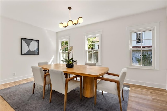 dining space with light hardwood / wood-style floors and a notable chandelier