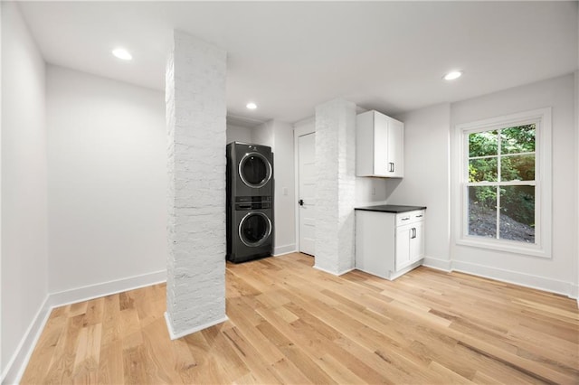 clothes washing area with decorative columns, light hardwood / wood-style flooring, and stacked washing maching and dryer