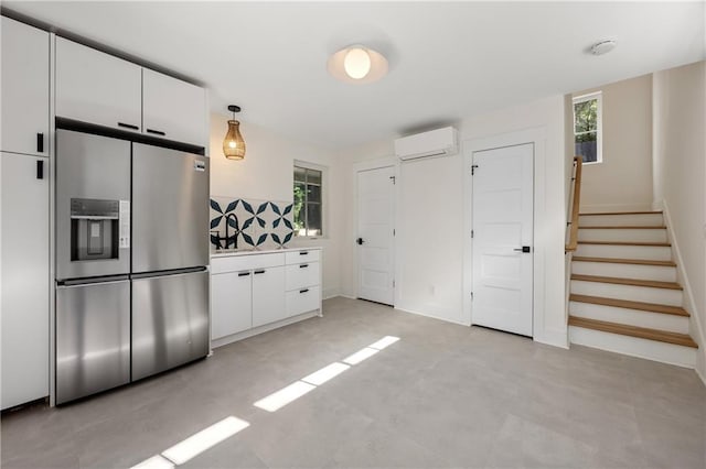 kitchen with white cabinetry, pendant lighting, a wall mounted air conditioner, and stainless steel refrigerator with ice dispenser