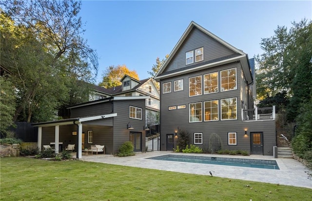 back of house featuring a patio, a balcony, and a lawn