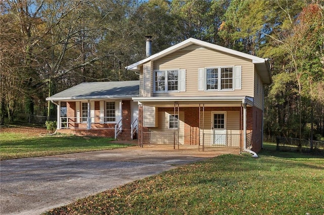 tri-level home featuring covered porch and a front lawn