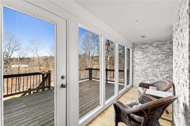 sunroom / solarium featuring plenty of natural light, wood finished floors, and a deck