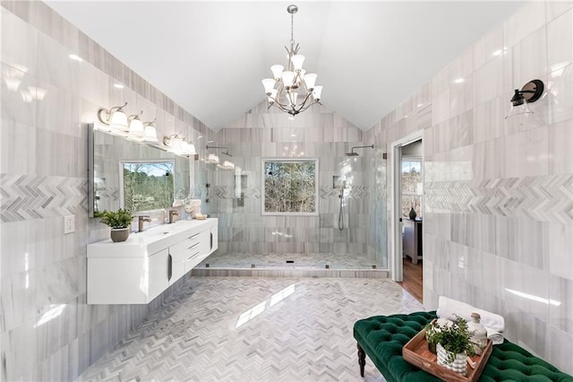 bathroom with a chandelier, a shower stall, tile walls, and vaulted ceiling