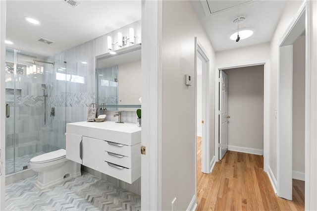 bathroom with visible vents, toilet, wood finished floors, a shower stall, and vanity
