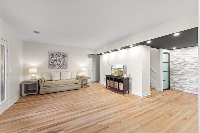 living area featuring visible vents, baseboards, stairs, and light wood finished floors