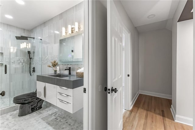 full bathroom with vanity, wood finished floors, a stall shower, and baseboards
