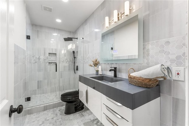 full bath with visible vents, backsplash, a shower stall, tile walls, and vanity