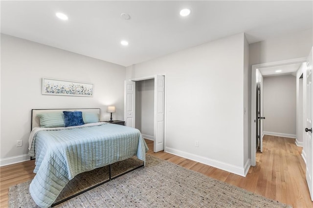 bedroom featuring recessed lighting, light wood-style floors, baseboards, and a closet