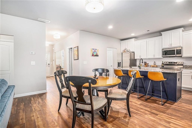 dining room with recessed lighting, visible vents, baseboards, and wood finished floors
