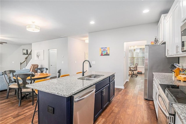 kitchen featuring dark wood-style floors, appliances with stainless steel finishes, white cabinets, and a sink